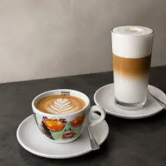 Zwei Kaffeespezialitäten: ein Cappuccino in einer bunten Tasse und ein Latte Macchiato im Glas. Die Frage "wie viel espresso in cappuccino" wird hier visuell beantwortet.
