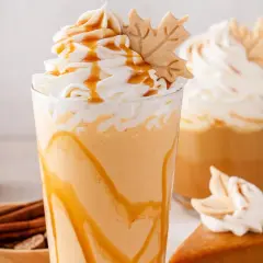 Cremiger Pumpkin Spice Latte mit Karamell und einem Blätter-Keks. Perfekt für gemütliche Herbsttage.