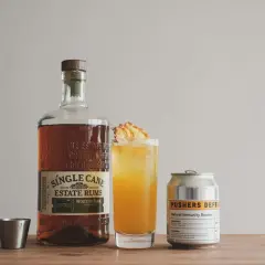 Flasche Single Cane Estate Rums, ein Cocktail mit Ananas und eine Dose "Pushers Defense". Der Rum hat seine Herkunft auf Jamaika.