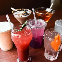 Verschiedene bunte Cocktails mit Eis und Garnituren. Ein cremiger Milchshake, ein roter Fruchtcocktail, ein lila Getränk und ein Gin Tonic. Gut zu wissen, dass Wodka glutenfrei ist!