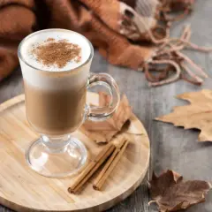 Ein warmer Herbst Kaffee mit Zimt, umgeben von Blättern und einer kuscheligen Decke.