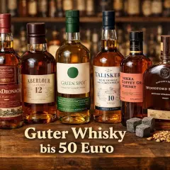 Sechs Flaschen edler Whiskys, darunter GlenDronach und Talisker, stehen bereit. Ein Glas mit bernsteinfarbener Flüssigkeit und Whiskysteine laden zum Genuss des besten Single Malts ein.