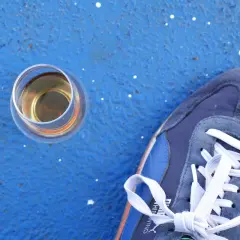 Ein Glas Whisky steht neben einem blauen Sneaker. Wer sich fragt, wie viel Kalorien hat Whisky, findet hier eine visuelle Anregung.