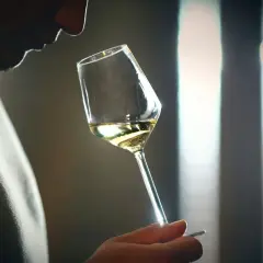 Mann riecht an einem Weinglas, der Wein riecht nach Aceton.
