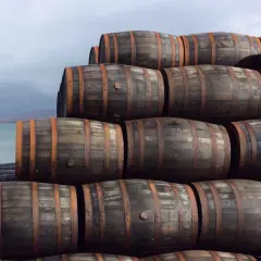 Stapel von Holzfässern am Wasser. Sie lagern dort, um die Reifung zu ermöglichen, was bedeutet, was bedeutet single malt.