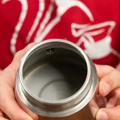Hände halten den oberen Teil eines Espressokochers. Der Innenraum ist leer und sauber, bereit für die Zubereitung von Kaffee.