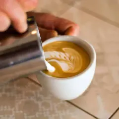 Barista verziert Cappuccino mit Milchschaum. So schmeckt Genuss!