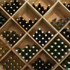 Holzregal mit vielen Flaschen Wein, ideal zum rotwein lagern. Verschiedene Sorten und Farben sind zu sehen.
