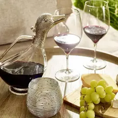 Ein Entenschnabel-Dekanter mit Rotwein, zwei Weingläser, Käse und Trauben auf einem Tablett – so gelingt das Wein richtig einschenken.