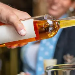 Ein Mann gießt goldbraunen Grappa in ein Glas. So trinkt man Grappa kalt, ein Genuss für besondere Momente.