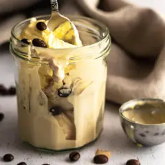 Cremiges Kaffee-Eis im Glas, perfekt für ein schnelles Rezept. Ein Löffel hebt das köstliche Eis hervor, umgeben von Kaffeebohnen.