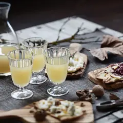 Erster Wein im Jahr: Gläser gefüllt mit hellem Wein, dazu Käse und Nüsse auf Holzbrettern.