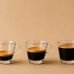 Drei Gläser mit unterschiedlichen Espresso varianten, von wenig bis viel Kaffee, mit cremiger Crema.