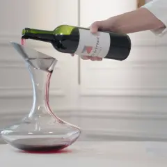 Ein Sommelier dekantiert sorgfältig Rotwein in eine Karaffe.