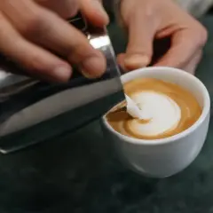 Barista zaubert mit Milch und Espresso ein Herz in die Tasse – ein Meisterwerk der Barista Art.