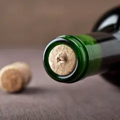 Nahaufnahme einer Weinflasche mit einem korken, der nicht rausgeht. Ein weiterer korken liegt daneben.