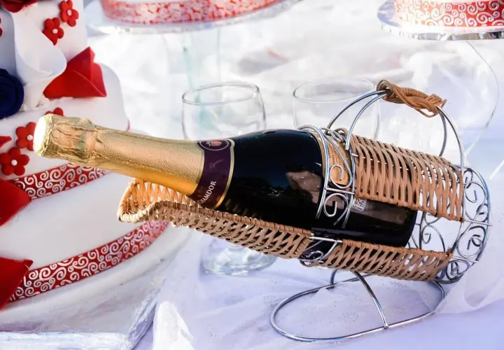Sektflasche in einem Weidenkorb, neben einer Hochzeitstorte. Das Wein-Ablaufdatum ist hier unwichtig, die Freude zählt.