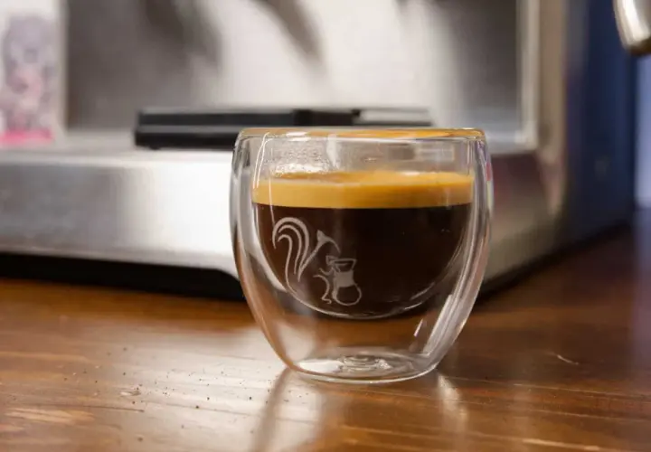 Ein dampfendes Espresso am Abend in einem doppelwandigen Glas mit einem süßen Eichhörnchen-Motiv. Perfekt für gemütliche Stunden.
