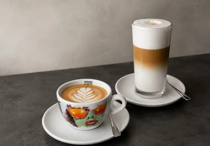 Zwei Kaffeespezialitäten: ein Cappuccino in einer bunten Tasse und ein Latte Macchiato im Glas. Die Frage "wie viel espresso in cappuccino" wird hier visuell beantwortet.