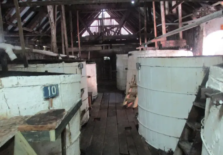 Große weiße Bottiche in einer alten Lagerhalle, vielleicht zur Herstellung von Rum-Inhaltsstoffen.