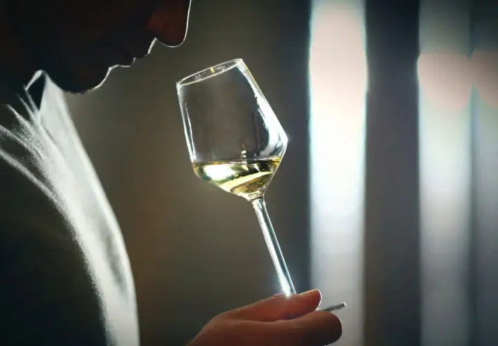 Mann riecht an einem Weinglas, der Wein riecht nach Aceton.