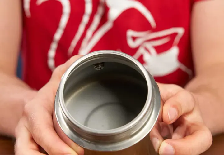 Hände halten den oberen Teil eines Espressokochers. Der Innenraum ist leer und sauber, bereit für die Zubereitung von Kaffee.