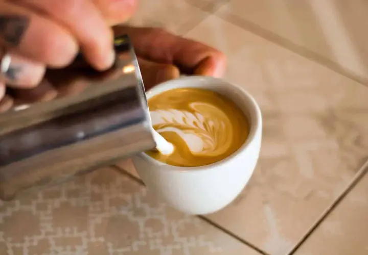 Barista verziert Cappuccino mit Milchschaum. So schmeckt Genuss!