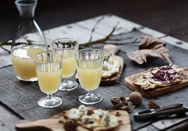Erster Wein im Jahr: Gläser gefüllt mit hellem Wein, dazu Käse und Nüsse auf Holzbrettern.