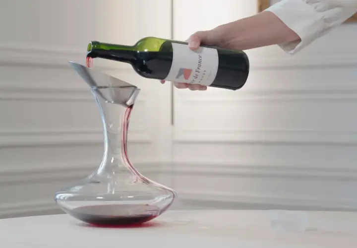 Ein Sommelier dekantiert sorgfältig Rotwein in eine Karaffe.