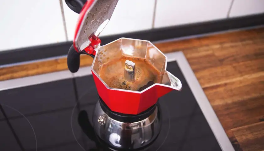 Rote Mokkakanne auf schwarzer Kochplatte, die frisch gebrühten Mokka Kaffee produziert.