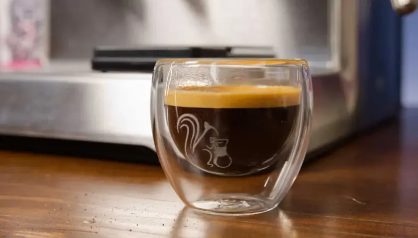 Ein dampfendes Espresso am Abend in einem doppelwandigen Glas mit einem süßen Eichhörnchen-Motiv. Perfekt für gemütliche Stunden.