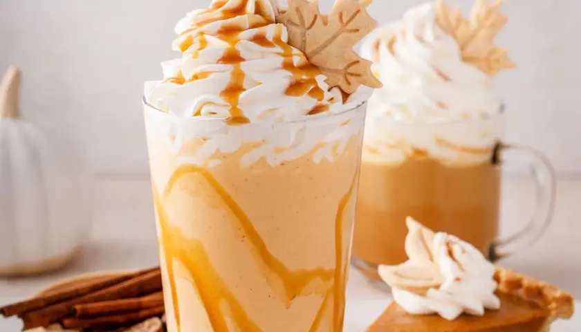 Cremiger Pumpkin Spice Latte mit Karamell und einem Blätter-Keks. Perfekt für gemütliche Herbsttage.
