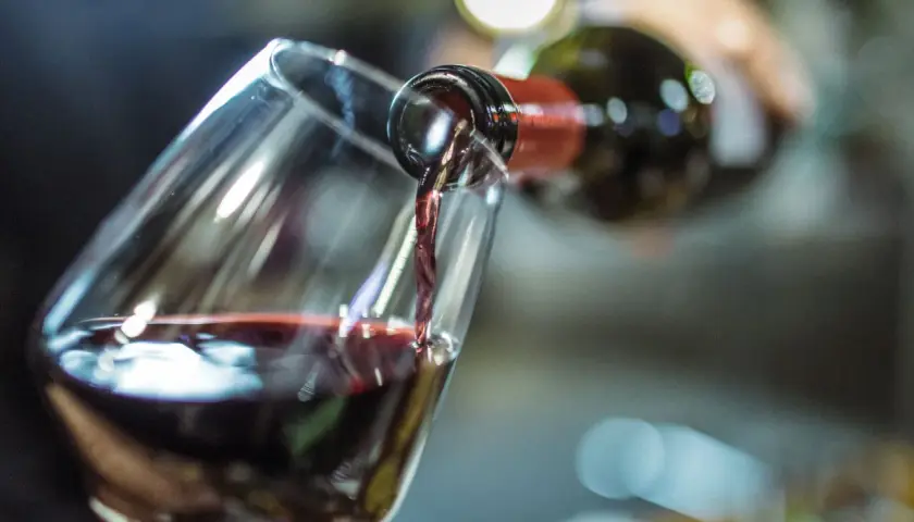 Rotwein wird in ein Glas gegossen. Die Frage, wie lange Rotwein offen haltbar ist, beschäftigt Genießer.