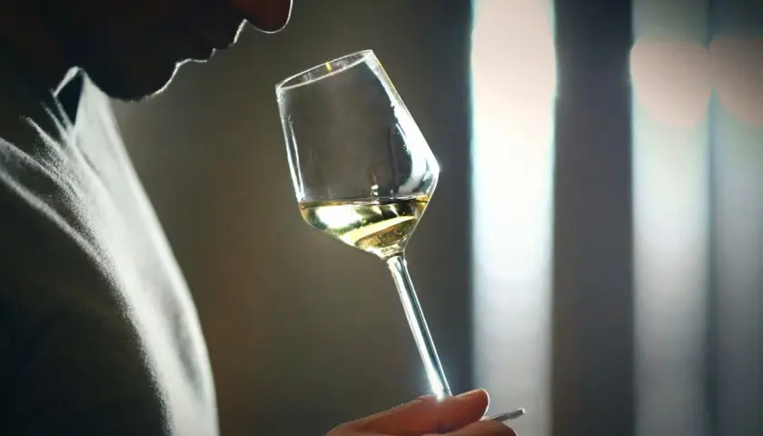 Mann riecht an einem Weinglas, der Wein riecht nach Aceton.