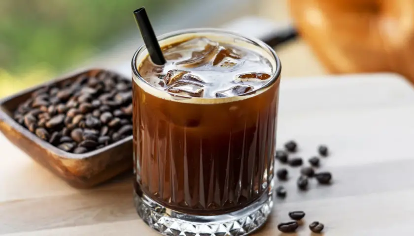 Erfrischender Cold Brew mit viel **cold brew koffein**. Eiswürfel und Kaffeebohnen daneben.