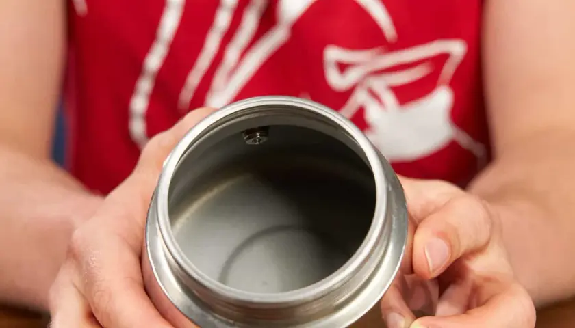 Hände halten den oberen Teil eines Espressokochers. Der Innenraum ist leer und sauber, bereit für die Zubereitung von Kaffee.