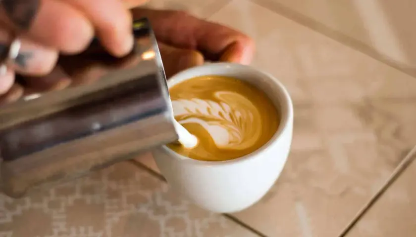 Barista verziert Cappuccino mit Milchschaum. So schmeckt Genuss!