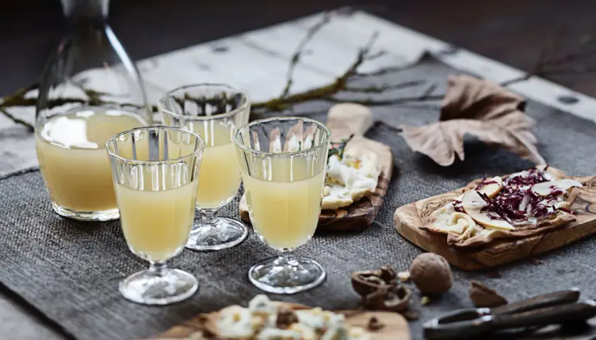 Erster Wein im Jahr: Gläser gefüllt mit hellem Wein, dazu Käse und Nüsse auf Holzbrettern.