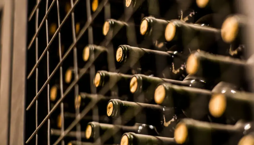 Weinregal mit vielen Flaschen. Man fragt sich, wie teuer ist der teuerste Wein der Welt, wenn selbst diese Flaschen so wertvoll aussehen.