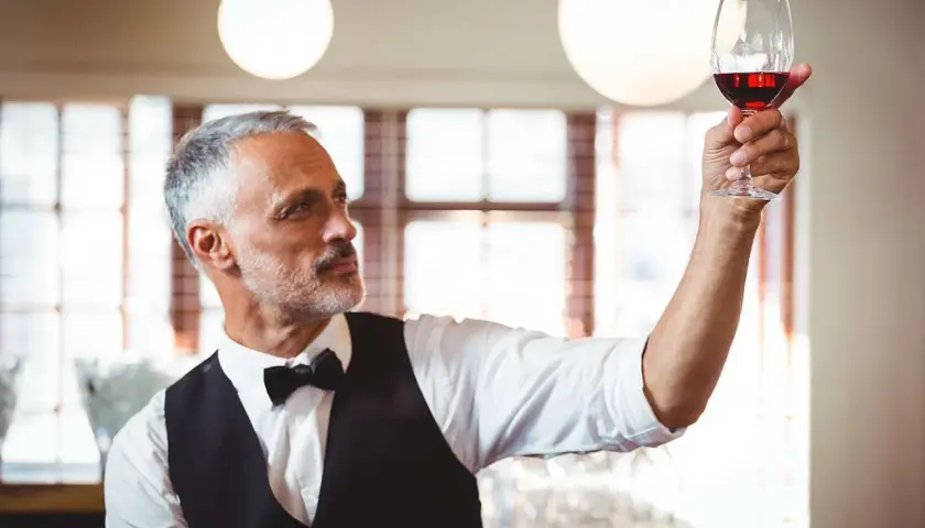 Ein erfahrener Sommelier, ein wahrer **master of wine**, prüft das tiefe Rot eines edlen Tropfens im Glas.