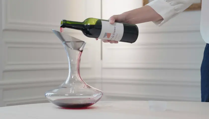 Ein Sommelier dekantiert sorgfältig Rotwein in eine Karaffe.