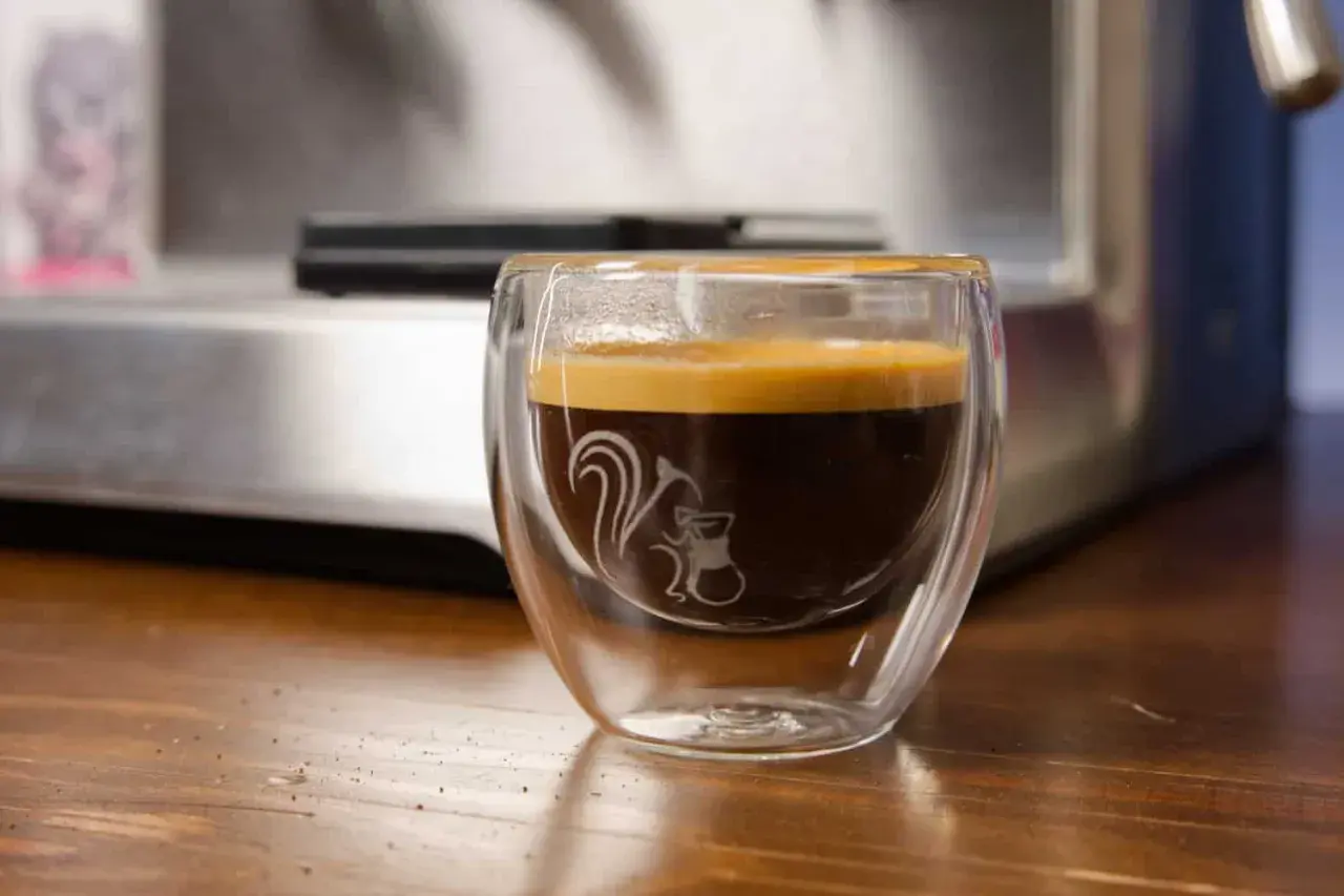 Ein dampfendes Espresso am Abend in einem doppelwandigen Glas mit einem süßen Eichhörnchen-Motiv. Perfekt für gemütliche Stunden.