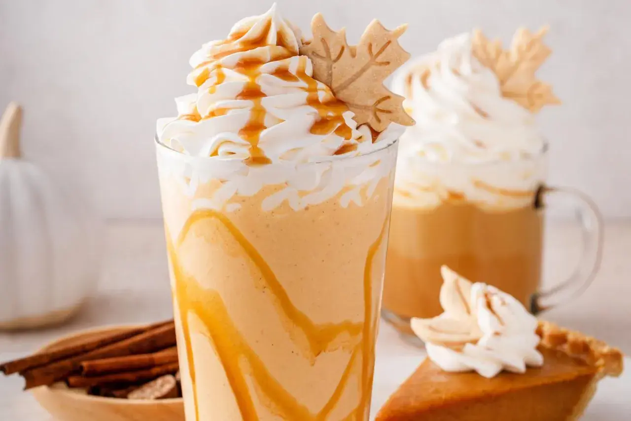 Cremiger Pumpkin Spice Latte mit Karamell und einem Blätter-Keks. Perfekt für gemütliche Herbsttage.