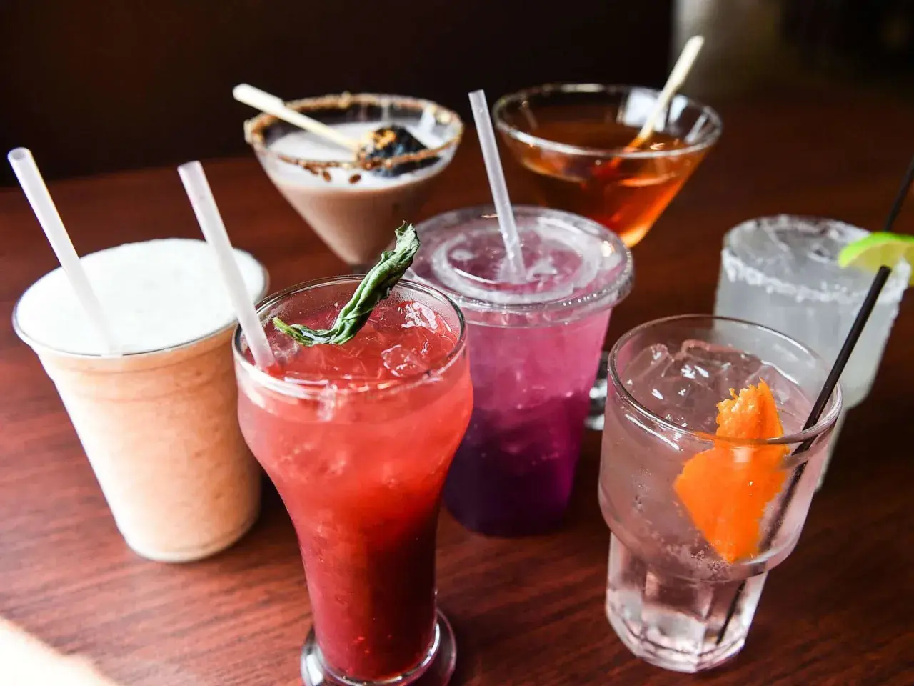 Verschiedene bunte Cocktails mit Eis und Garnituren. Ein cremiger Milchshake, ein roter Fruchtcocktail, ein lila Getränk und ein Gin Tonic. Gut zu wissen, dass Wodka glutenfrei ist!