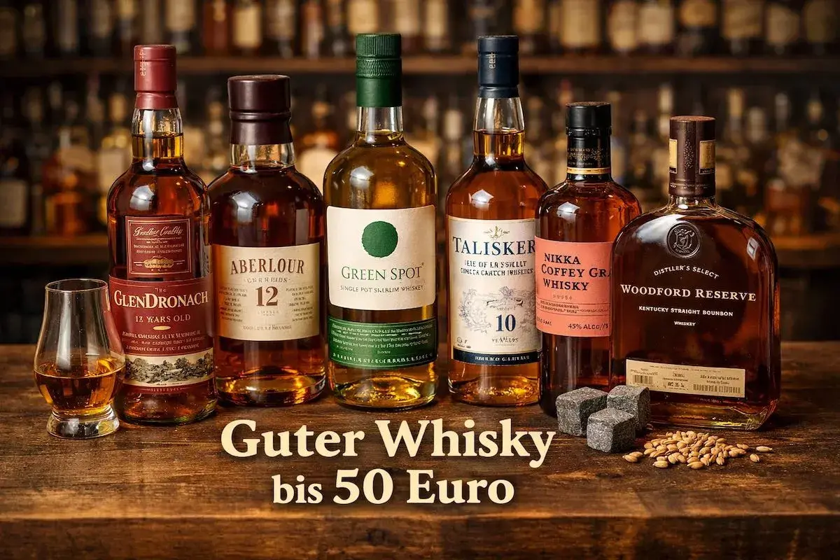 Sechs Flaschen edler Whiskys, darunter GlenDronach und Talisker, stehen bereit. Ein Glas mit bernsteinfarbener Flüssigkeit und Whiskysteine laden zum Genuss des besten Single Malts ein.