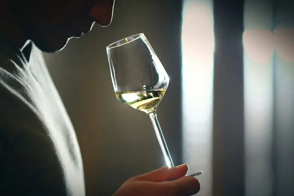 Mann riecht an einem Weinglas, der Wein riecht nach Aceton.