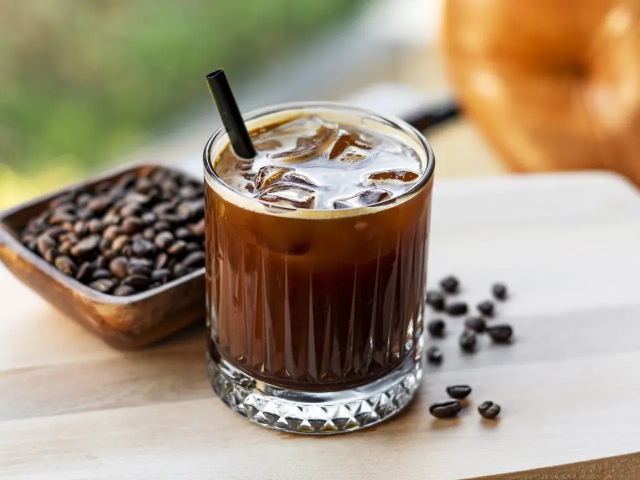 Erfrischender Cold Brew mit viel **cold brew koffein**. Eiswürfel und Kaffeebohnen daneben.