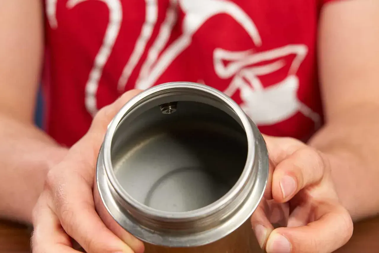 Hände halten den oberen Teil eines Espressokochers. Der Innenraum ist leer und sauber, bereit für die Zubereitung von Kaffee.