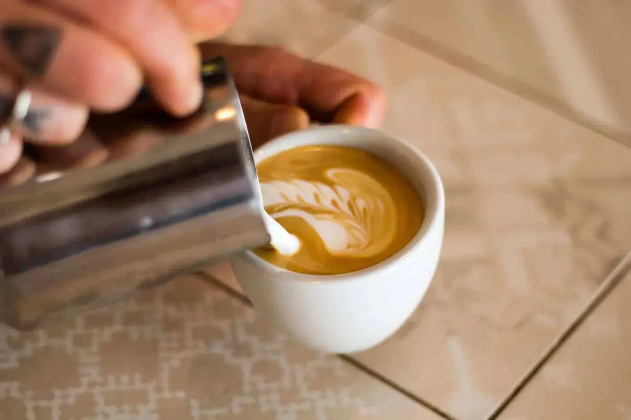 Barista verziert Cappuccino mit Milchschaum. So schmeckt Genuss!