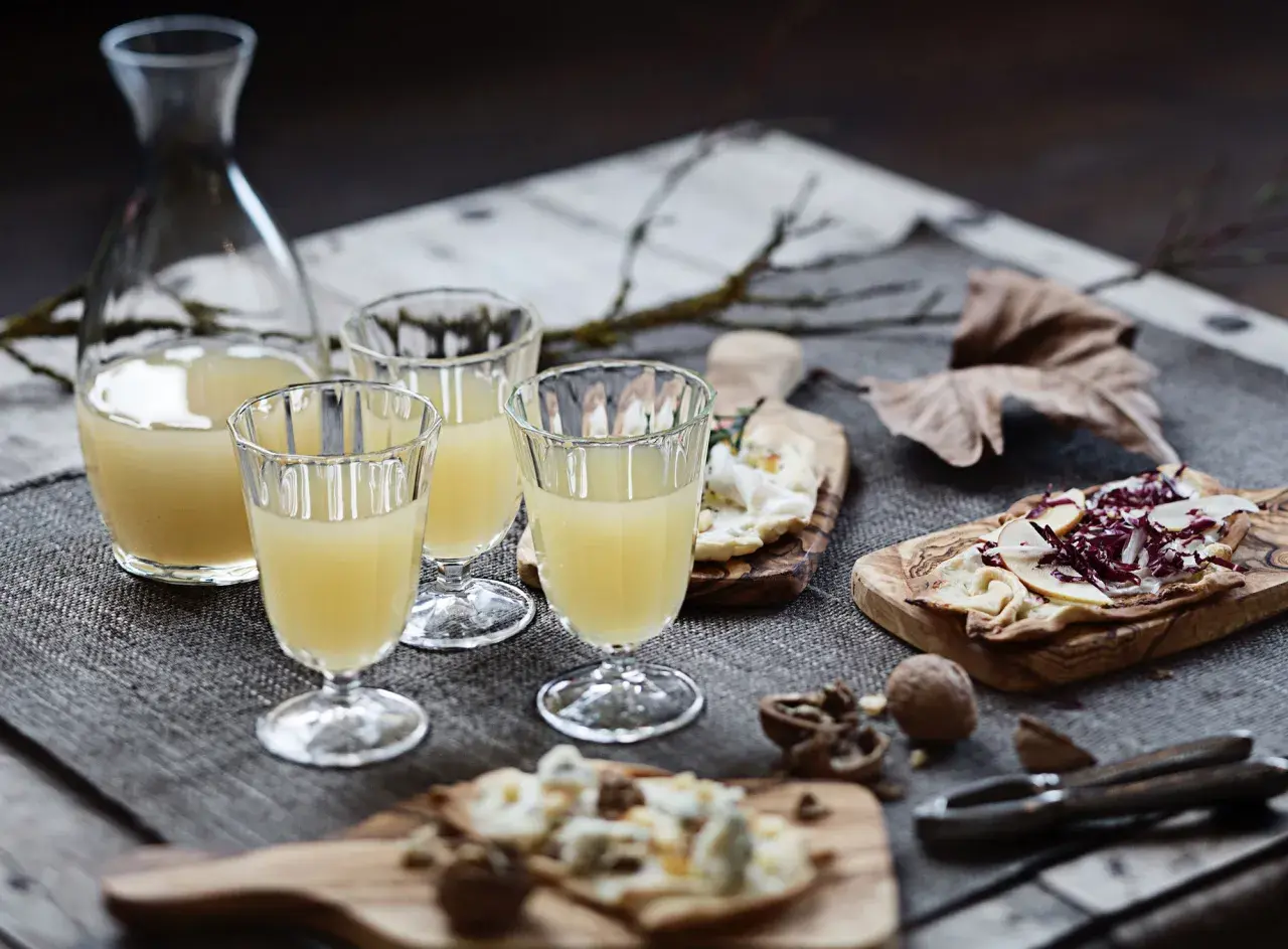 Erster Wein im Jahr: Gläser gefüllt mit hellem Wein, dazu Käse und Nüsse auf Holzbrettern.